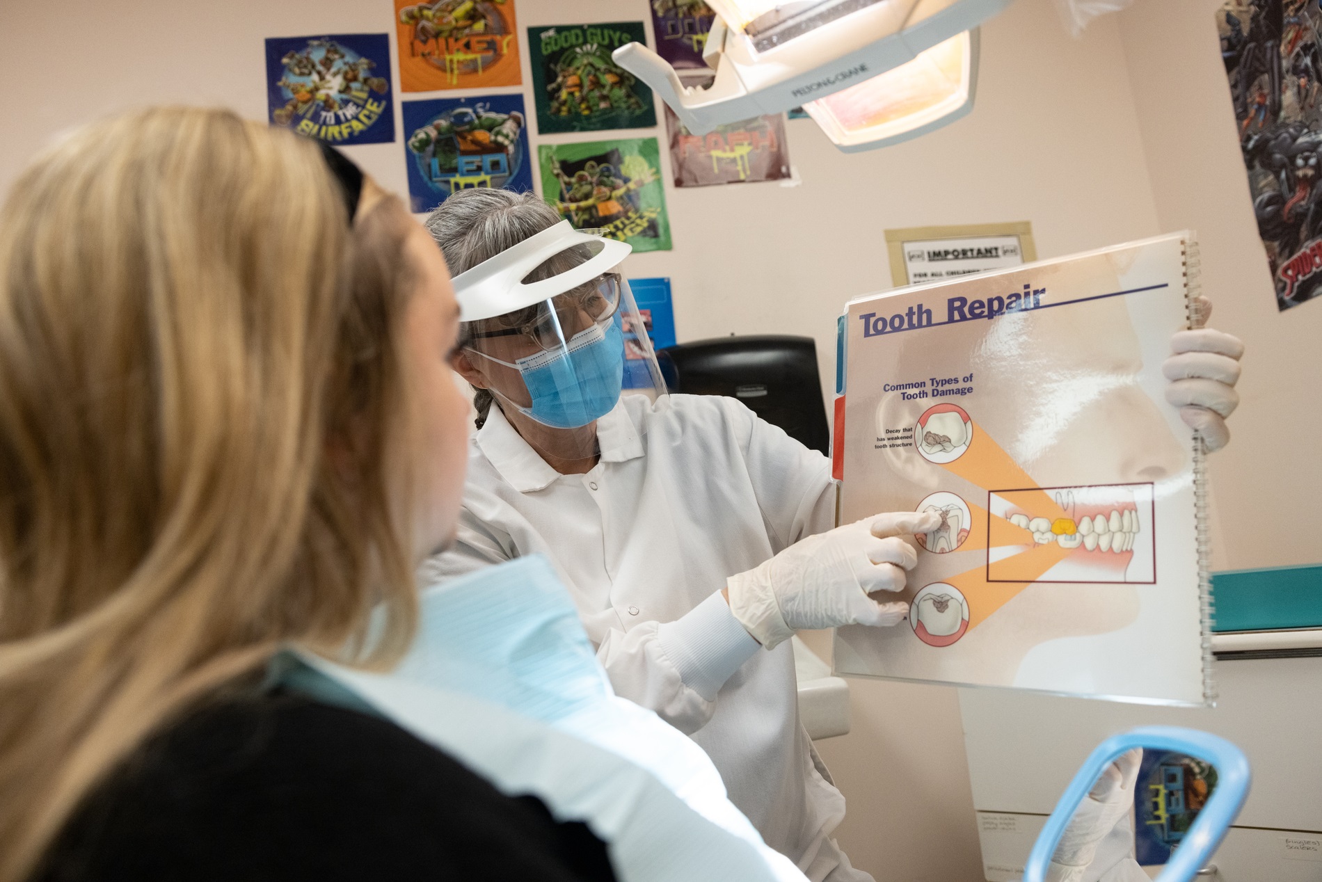 Dentist holding up an infographic of tooth repair to a patient