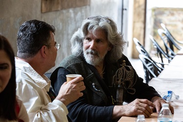 Men in Scottish attire having a friendly discussion about Outlander.