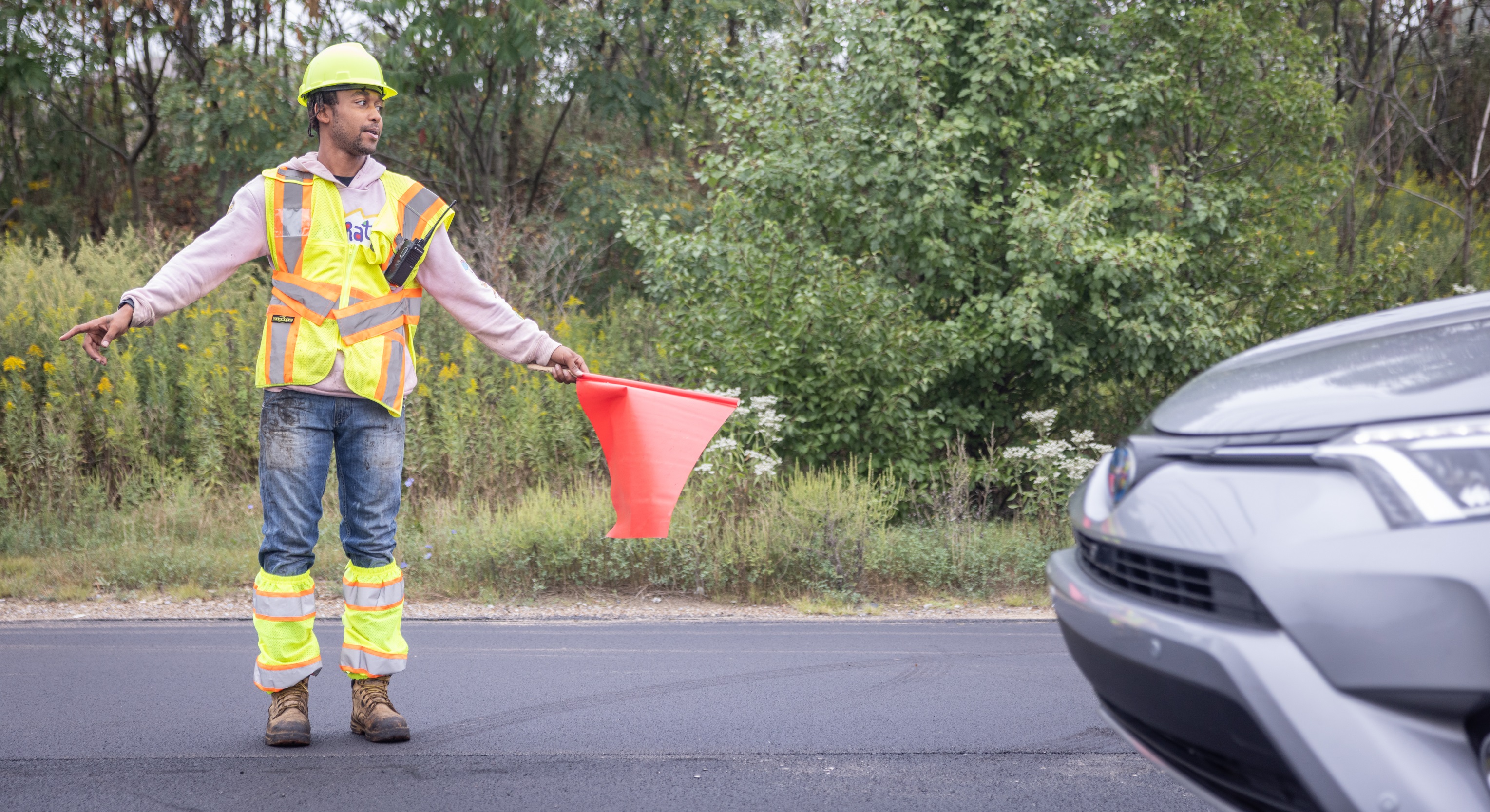 A flagger directs a car through a construction work zone